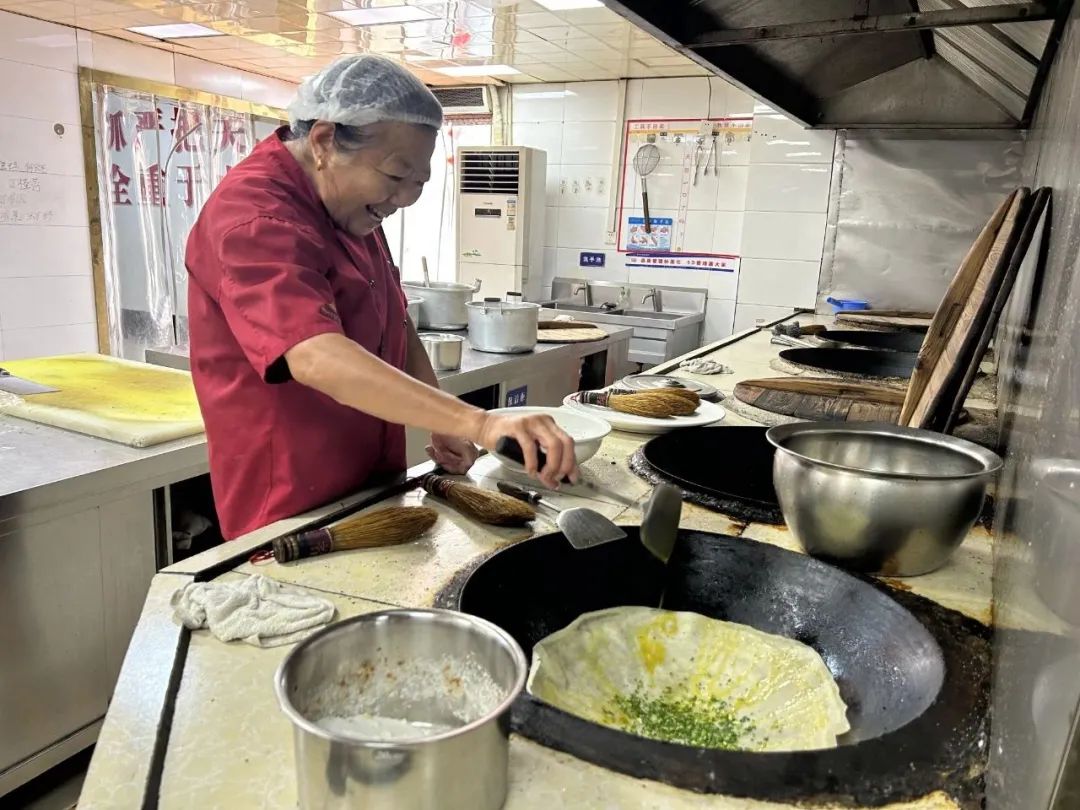 祁巷村村民余蘭珍在農家樂中央廚房內攤煎餅。人民網 王丹丹攝